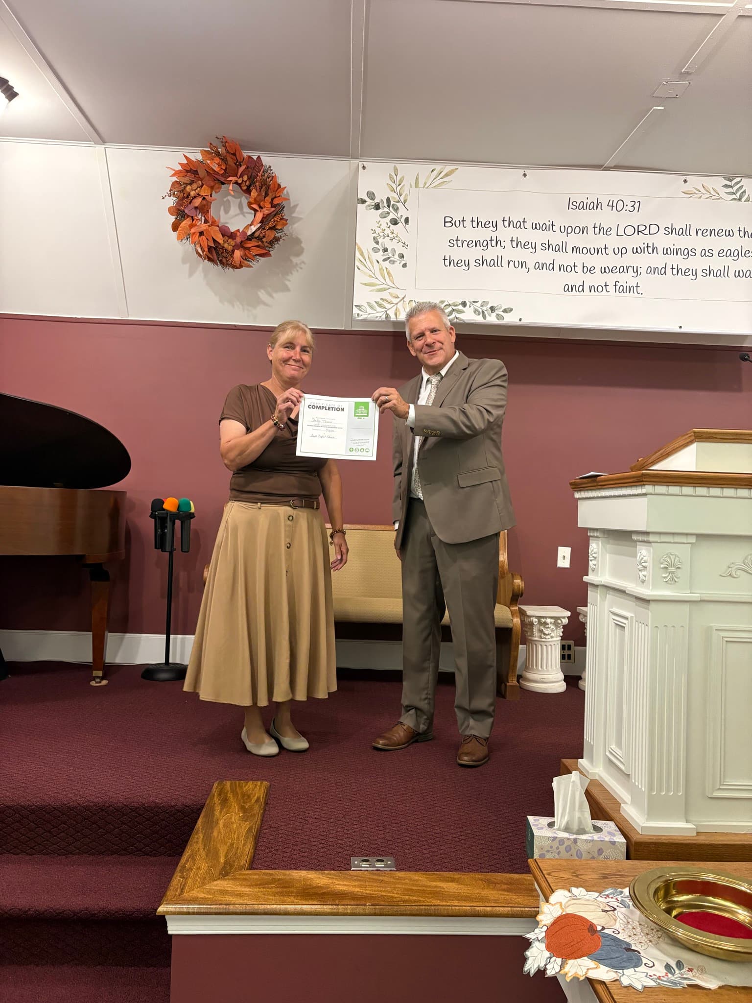 A church member receiving a discipleship certificate in the sanctuary