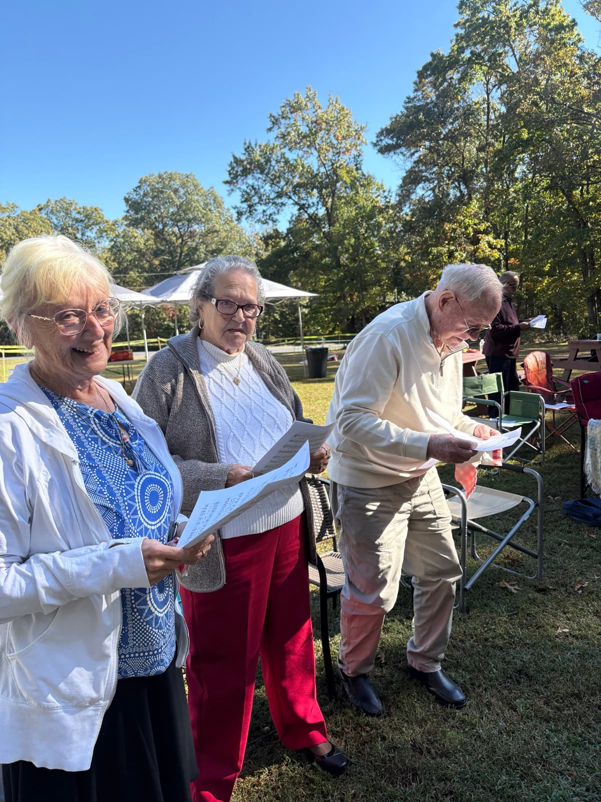 Church members singing hymns outdoors on a sunny autumn day